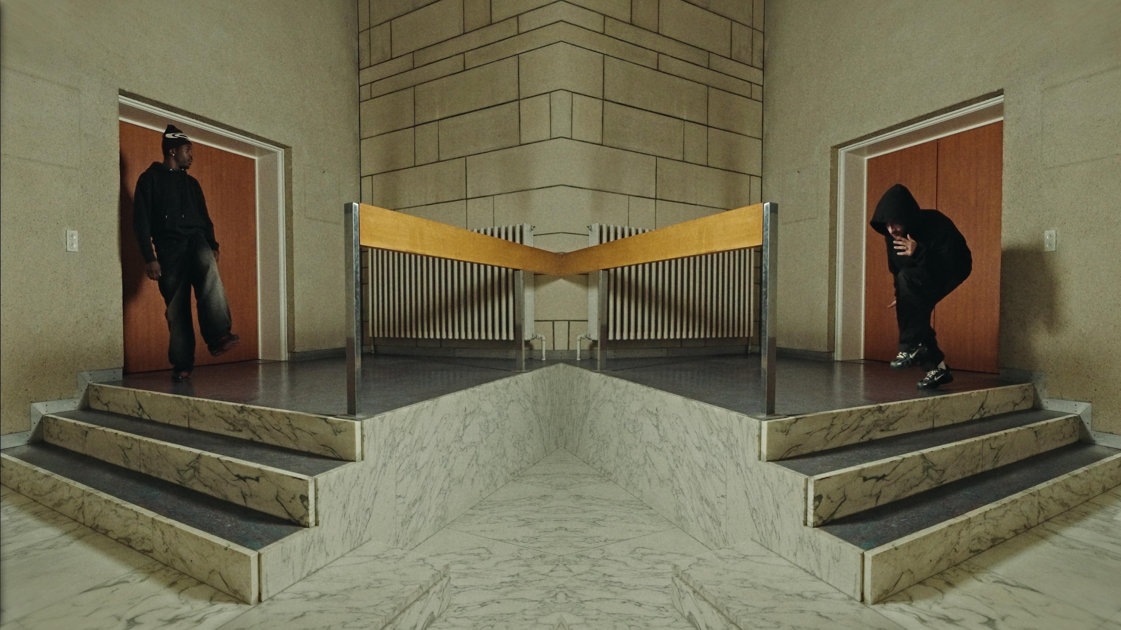 Two dancers facing each other across a mirrored staircase.
